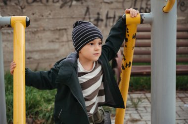 Mutlu çocuk sonbaharda oyun parkında yatay barlarda oynuyor.