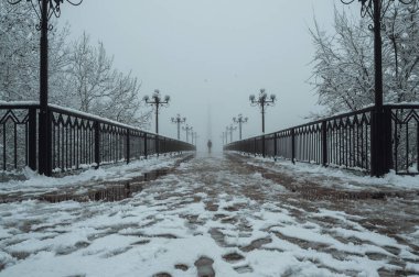Siluet sırtlı adam manyak sisli bir köprüde yürüyor kışın karlı ve sisli fenerlerle