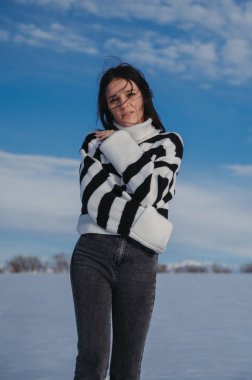 Mutlu Kafkasyalı esmer kız kışın karlı bir tarlada gülümsüyor.