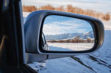 Tien Shan Dağları 'nın olduğu güzel kış manzarası ve arabanın dikiz aynasında karların üzerinde ağaçlar. Kazakistan 'da bayram tatili tatili kavramı