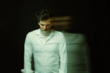 Zihinsel bozuklukları ve akıl hastalıkları olan, siyah arka planda deli gömleği giymiş bir adamın şizofren portresi.