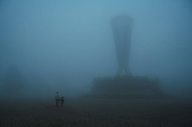 Akşamları sisli mistik bir parkta yürüyen çocuklu bir anne kadının sırtından. Sonbaharda, Kazakistan 'ın Şymkent kentindeki Independence Park' ta sisli bir sis bulutunda, insanların olduğu sisli bir manzara.