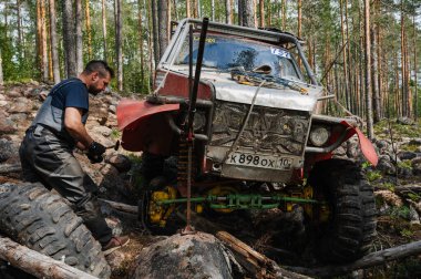 KARELİYA, RUSSIA REUKLİK - CIRCA HAZİRAN, 2022: Ladoga Gölü çevresindeki off-road turnuvası Ladoga Kupası 2022. Yarışçılar arazi aracının tekerini tamir ederler.
