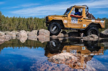 KARELİYA, RUSSIA REUKLİK - CIRCA HAZİRAN, 2022: Ladoga Gölü çevresindeki off-road turnuvası Ladoga Kupası 2022. 4x4 Mercedes göl kıyısındaki kayalıklarda geziniyor.