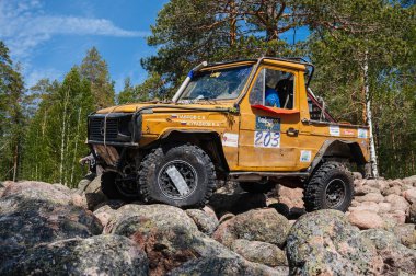 KARELİYA, RUSSIA REUKLİK - CIRCA HAZİRAN, 2022: Ladoga Gölü çevresindeki off-road turnuvası Ladoga Kupası 2022. 4x4 Mercedes off-road yarışında kayaların üzerinden geçiyor.