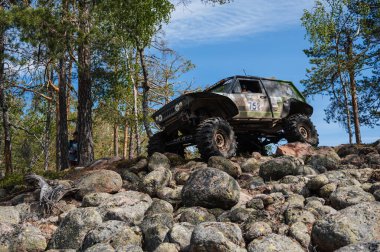 KARELİYA, RUSSIA REUKLİK - CIRCA HAZİRAN, 2022: Ladoga Gölü çevresindeki off-road turnuvası Ladoga Kupası 2022. 4x4 SUV yazın doğada bir off-road yarışında kayaların üzerinden geçer.