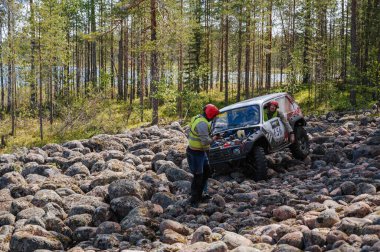 KARELİYA, RUSSIA REUKLİK - CIRCA HAZİRAN, 2022: Ladoga Gölü çevresindeki off-road turnuvası Ladoga Kupası 2022. Niva 4x4 off-road arabaları ormanın ortasında kayalıklarda yarışır.