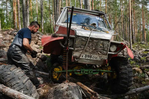KARELİYA, RUSSIA REUKLİK - CIRCA HAZİRAN, 2022: Ladoga Gölü çevresindeki off-road turnuvası Ladoga Kupası 2022. Yarışçılar arazi aracının tekerini tamir ederler.