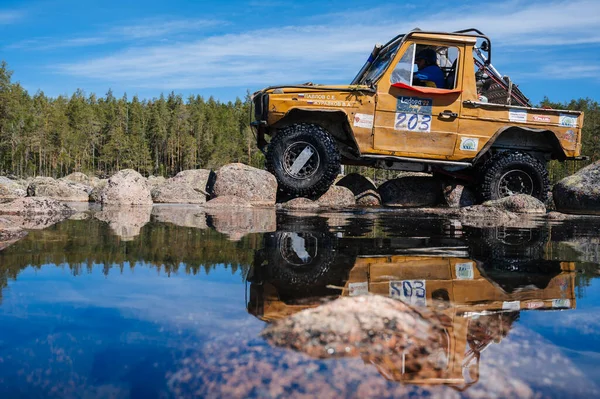 KARELİYA, RUSSIA REUKLİK - CIRCA HAZİRAN, 2022: Ladoga Gölü çevresindeki off-road turnuvası Ladoga Kupası 2022. 4x4 Mercedes göl kıyısındaki kayalıklarda geziniyor.