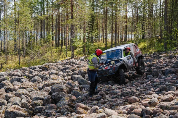 KARELİYA, RUSSIA REUKLİK - CIRCA HAZİRAN, 2022: Ladoga Gölü çevresindeki off-road turnuvası Ladoga Kupası 2022. Niva 4x4 off-road arabaları ormanın ortasında kayalıklarda yarışır.