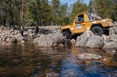 KARELİYA, RUSSIA REUKLİK - CIRCA HAZİRAN, 2022: Ladoga Gölü çevresindeki off-road turnuvası Ladoga Kupası 2022. 4x4 Mercedes yazın doğada bir off-road yarışında kayaların üzerinden geçiyor.