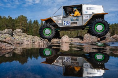 KARELİYA, RUSSIA REUKLİK - CIRCA HAZİRAN, 2022: Ladoga Gölü çevresindeki off-road turnuvası Ladoga Kupası 2022. 4x4 SUV yazın doğada bir off-road yarışında göl kenarında kayalıklarda gezer.