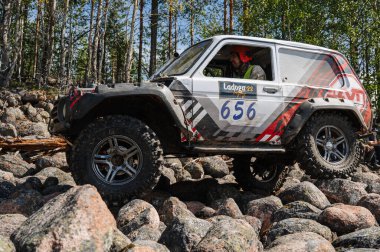 KARELİYA, RUSSIA REUKLİK - CIRCA HAZİRAN, 2022: Ladoga Gölü çevresindeki off-road turnuvası Ladoga Kupası 2022. Niva 4x4 off-road arabaları ormanın ortasında kayalıklarda yarışır.