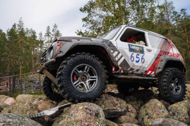KARELİYA, RUSSIA REUKLİK - CIRCA HAZİRAN, 2022: Ladoga Gölü çevresindeki off-road turnuvası Ladoga Kupası 2022. Off-road cipi Niva 4x4 araba doğada kayalıklarda yarışır.