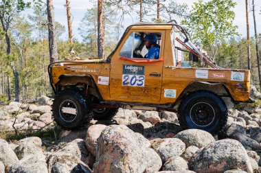 KARELİYA, RUSSIA REUKLİK - CIRCA HAZİRAN, 2022: Ladoga Gölü çevresindeki off-road turnuvası Ladoga Kupası 2022. 4x4 Mercedes off-road yarışında kayaların üzerinden geçiyor.