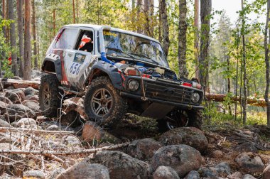 KARELİYA, RUSSIA REUKLİK - CIRCA HAZİRAN, 2022: Ladoga Gölü çevresindeki off-road turnuvası Ladoga Kupası 2022. Niva 4x4 off-road arabaları ormanın ortasında kayalıklarda yarışır.