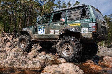 KARELİYA, RUSSIA REUKLİK - CIRCA HAZİRAN, 2022: Ladoga Gölü çevresindeki off-road turnuvası Ladoga Kupası 2022. 4x4 SUV yazın doğada bir off-road yarışında kayaların üzerinden geçer.