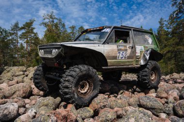 KARELİYA, RUSSIA REUKLİK - CIRCA HAZİRAN, 2022: Ladoga Gölü çevresindeki off-road turnuvası Ladoga Kupası 2022. 4x4 SUV yazın doğada bir off-road yarışında kayaların üzerinden geçer.
