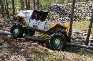 KARELİYA, RUSSIA REUKLİK - CIRCA HAZİRAN, 2022: Ladoga Gölü çevresindeki off-road turnuvası Ladoga Kupası 2022. 4x4 Jeep arazi aracı ormanın ortasında kayaların üzerinden geçiyor.