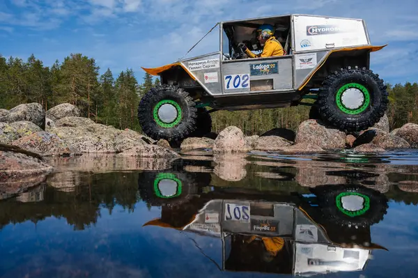 KARELİYA, RUSSIA REUKLİK - CIRCA HAZİRAN, 2022: Ladoga Gölü çevresindeki off-road turnuvası Ladoga Kupası 2022. 4x4 SUV yazın doğada bir off-road yarışında göl kenarında kayalıklarda gezer.