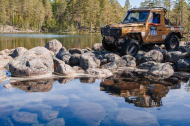 KARELIA, RUSSIA - CIRCA JUNE, 2022: Ladoga Gölü çevresindeki Off-road turnuvası Ladoga Kupası 2022. 4x4 Mercedes göl kıyısındaki kayalıklarda geziniyor.