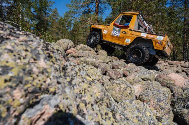 KARELIA, RUSSIA - CIRCA JUNE, 2022: Ladoga Gölü çevresindeki Off-road turnuvası Ladoga Kupası 2022. 4x4 Mercedes off-road yarışında kayaların üzerinden geçiyor.