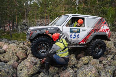 KARELIA, RUSSIA - CIRCA JUNE, 2022: Ladoga Gölü çevresindeki Off-road turnuvası Ladoga Kupası 2022. Off-road cipi Niva 4x4 araba doğada kayalıklarda yarışır.