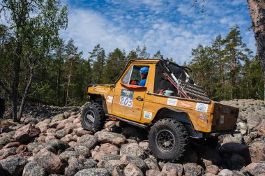 KARELIA, RUSSIA - CIRCA JUNE, 2022: Ladoga Gölü çevresindeki Off-road turnuvası Ladoga Kupası 2022. 4x4 Mercedes yazın doğada bir off-road yarışında kayaların üzerinden geçiyor.