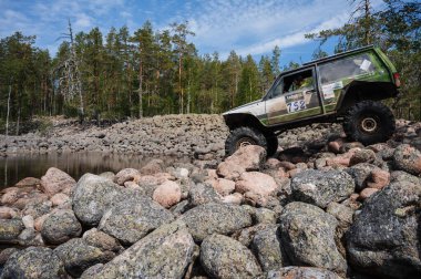 KARELIA, RUSSIA - CIRCA JUNE, 2022: Ladoga Gölü çevresindeki Off-road turnuvası Ladoga Kupası 2022. 4x4 SUV yazın doğada bir off-road yarışında kayaların üzerinden geçer.