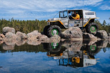 KARELIA, RUSSIA - CIRCA JUNE, 2022: Ladoga Gölü çevresindeki Off-road turnuvası Ladoga Kupası 2022. 4x4 SUV yazın doğada bir off-road yarışında göl kenarında kayalıklarda gezer.