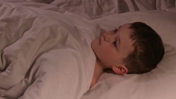 睁开眼睛的小男孩晚上不能睡在卧室的床上做梦 孩子们在毛毯下面的枕头上看着天花板 — 图库视频影像