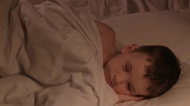幸せな少年は夜の寝室で寝ている かわいい赤ん坊の息子は夜の毛布の下の枕で寝ています — ストック動画