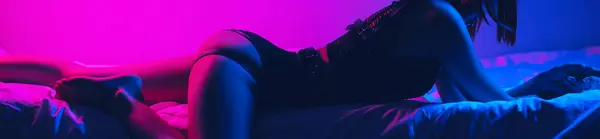 woman girl with a sexy body and ass on a bed in a bedroom with a neon light. Wide horizontal banner header