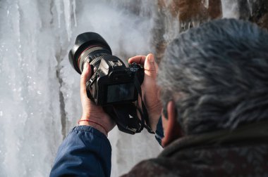 Fotoğrafçılar modern bir DSLR kamerasıyla kışın buz saçaklarını yakın plan çekiyorlar.