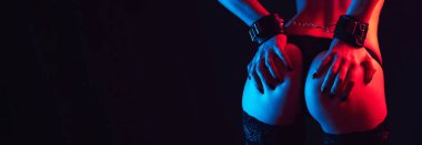 Submissive woman bottom slave girl with sexy ass with hands in leather handcuffs. BDSM sex with submission and domination. Wide banner on a black background