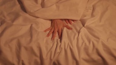 Kadın kadın kız ellerini seks ve orgazm için uzatıyor ve beyaz çarşafı yatağa sarıp sıkıyor.