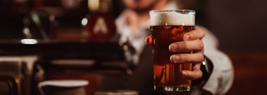 Barmen elinde bir bardak hafif bira barında köpüklü bira servisi yapar.