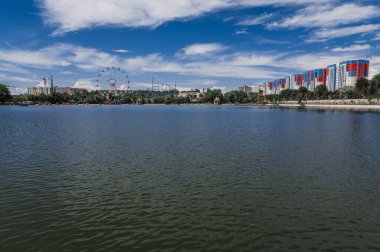 SHYMKENT, KAZAKHSTAN - 07 Temmuz 2023: Yazın Şymkent 'teki gölden Altyn Göz Parkı ve dönme dolap manzarası
