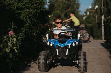 Oğlan yazın parkta oyuncak bir mini arabaya biner.