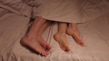 Bir erkek ve bir kadın akşamları yatak odasındaki bir yatakta uyuyakalırlar. Bir çift erkek ve kadın ayağı, battaniyenin altında bir çarşafın üzerinde uyurken gece hareket eder.
