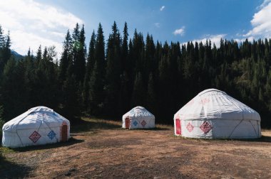 Yazın Kazakistan bozkırlarında, ormanın yakınındaki geleneksel Asya göçebe beyaz yurtlar.