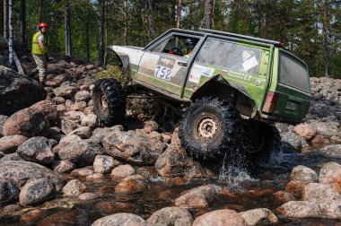 KARELIA, RUSSIA - CIRCA JUNE, 2022: Ladoga Gölü çevresindeki Off-road turnuvası Ladoga Kupası 2022. 4x4 SUV yazın doğada bir off-road yarışında kayaların üzerinden geçer.