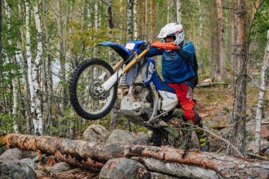 KARELİYA, RUSSIA REÜKLİK - CIRCA HAZİRAN 2022: Karelia 'da Ladoga Kupası 2022 off-road turnuvası. Spor motosikletli motosiklet yarışçısı zorlu yarış pistinde engelin üzerinden atlar