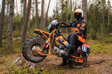KARELİYA, RUSSIA REÜKLİK - CIRCA HAZİRAN 2022: Karelia 'da Ladoga Kupası 2022 off-road turnuvası. Kasklı profesyonel motosiklet yarışçısı ormanda spor motosikletinde poz veriyor.
