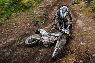 KARELİYA, RUSSIA REÜKLİK - CIRCA HAZİRAN 2022: Karelia 'da Ladoga Kupası 2022 off-road turnuvası. Enduro spor bisikletli bir motosikletçi düştükten sonra bir motosiklet alır.