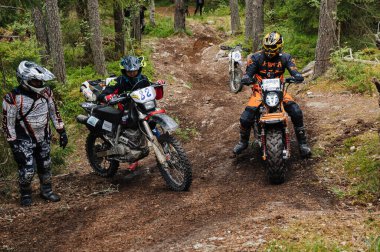 KARELİYA, RUSSIA REÜKLİK - CIRCA HAZİRAN 2022: Karelia 'da Ladoga Kupası 2022 off-road turnuvası. Enduro spor motosikletli motosikletçiler bir motokros yarışında ormanda kayalık bir tepeye tırmanırlar.
