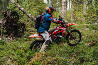 KARELİYA, RUSSIA REÜKLİK - CIRCA HAZİRAN 2022: Karelia 'da Ladoga Kupası 2022 off-road turnuvası. Motosiklet yarışçısı motorsiklet motosikletini hareket bulanıklığıyla zorlu arazide sürüyor.