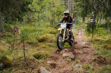 KARELİYA, RUSSIA REÜKLİK - CIRCA HAZİRAN 2022: Karelia 'da Ladoga Kupası 2022 off-road turnuvası. Motosiklet yarışçısı motorsiklet motosikletini hareket bulanıklığıyla zorlu arazide sürüyor.