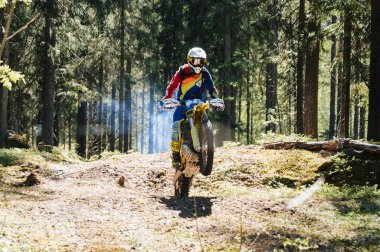 KARELİYA, RUSSIA REÜKLİK - CIRCA HAZİRAN 2022: Karelia 'da Ladoga Kupası 2022 off-road turnuvası. Spor motosikletli bir motosiklet yarışçısı ormanda bir motokros yarışmasında tepeden atlıyor.