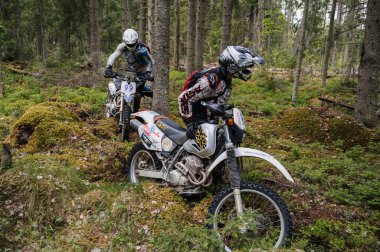 KARELİYA, RUSSIA REÜKLİK - CIRCA HAZİRAN 2022: Karelia 'da Ladoga Kupası 2022 off-road turnuvası. Motosikletliler ormanda bir motokros yarışında bir motosikleti kayaların üzerinden sürüklerler.